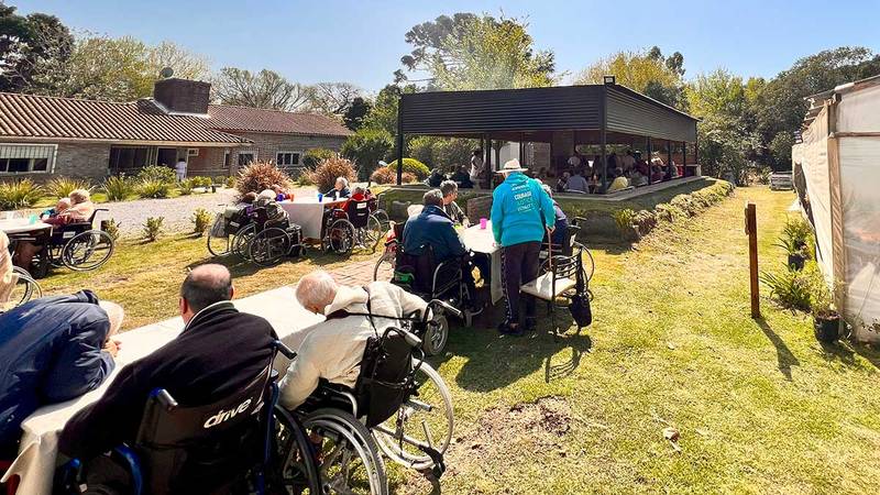 Residentes compartiendo una comida en el jardín, frente al quincho